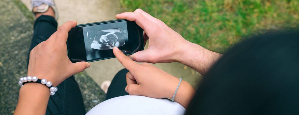 Pregnant looking ultrasound scan on phone with her couple